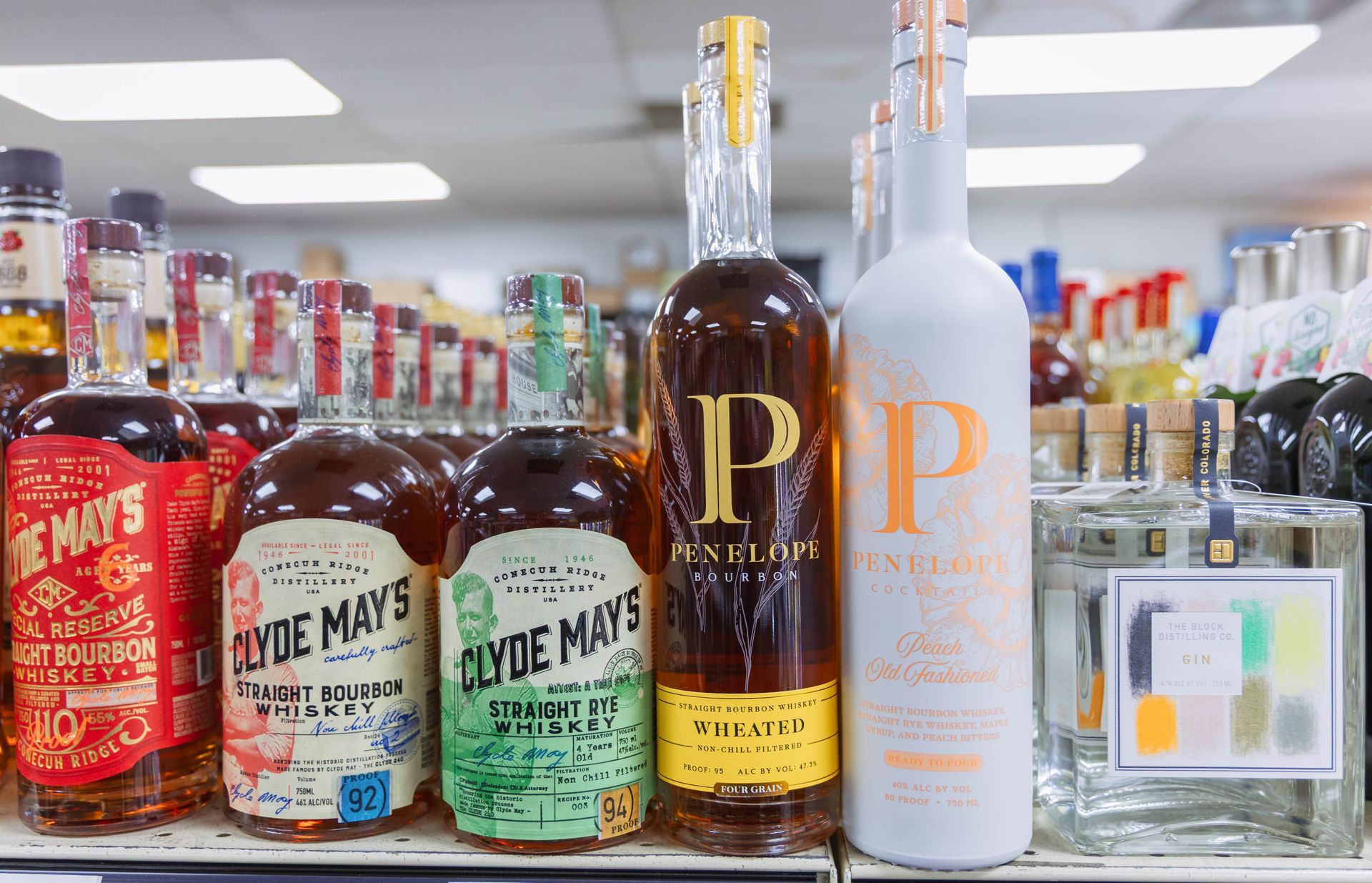 Bottles of liquor on a store shelf.  Includes Clyde May's whiskey in various bottles.