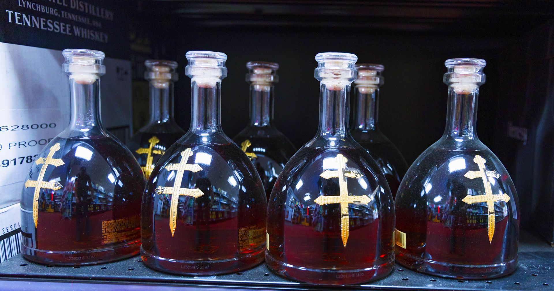 Bottles of dark amber liquor with gold crosses on a shelf.