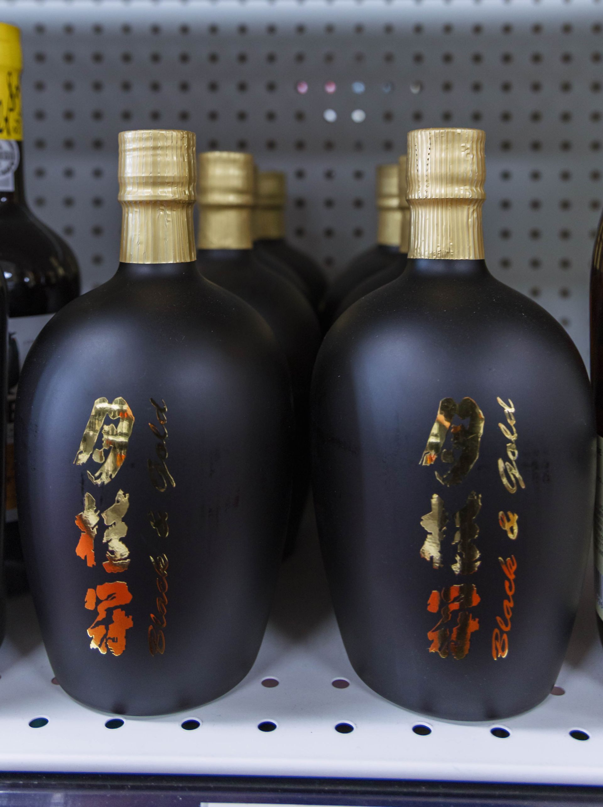 Black liquor bottles with gold caps and labels, arranged on a shelf.