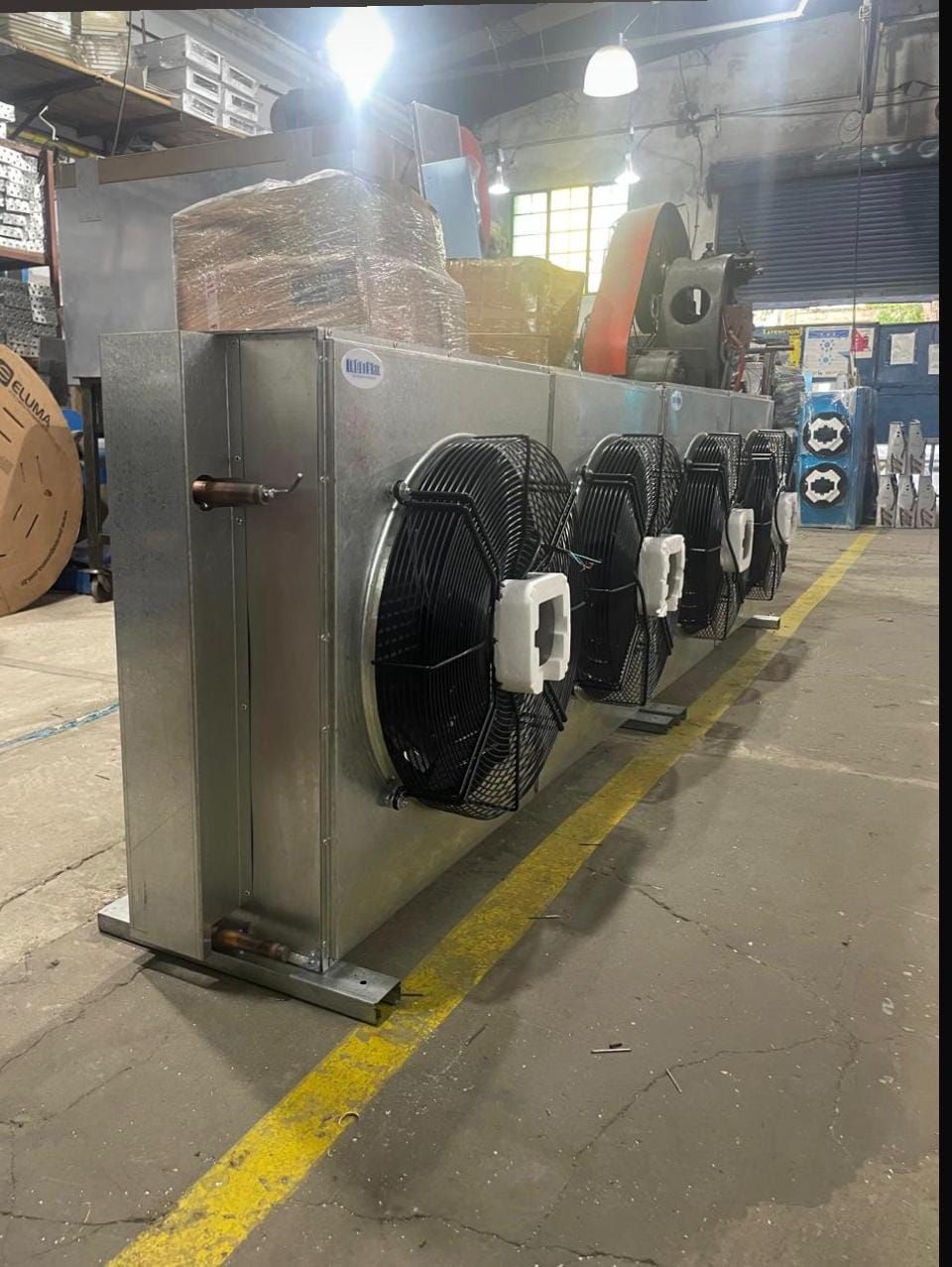 Gran unidad industrial metálica con cuatro ventiladores negros en un pasillo de almacén.