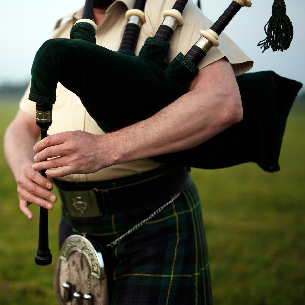 A man in a kilt is holding a bagpipe
