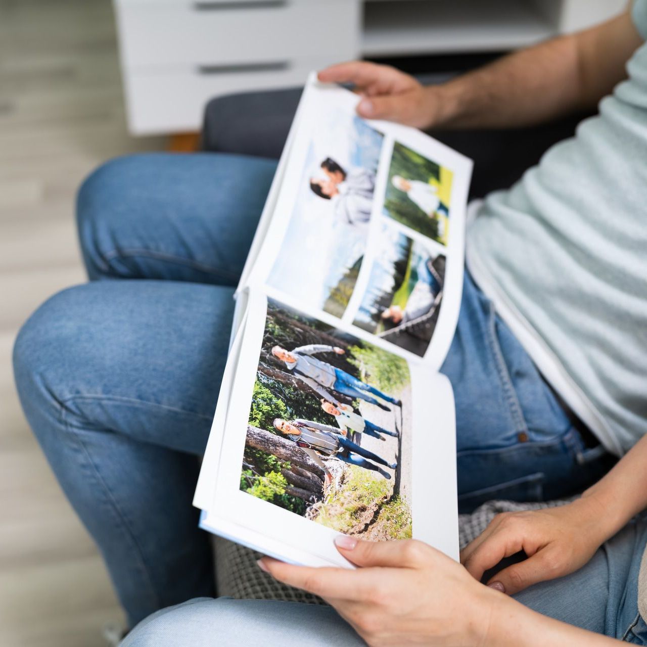 A man and a woman are sitting on a couch looking at a photo album.