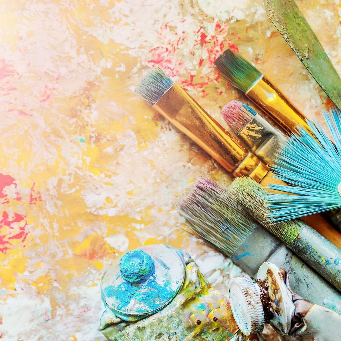 A bunch of paint brushes sitting on top of a palette on a table.