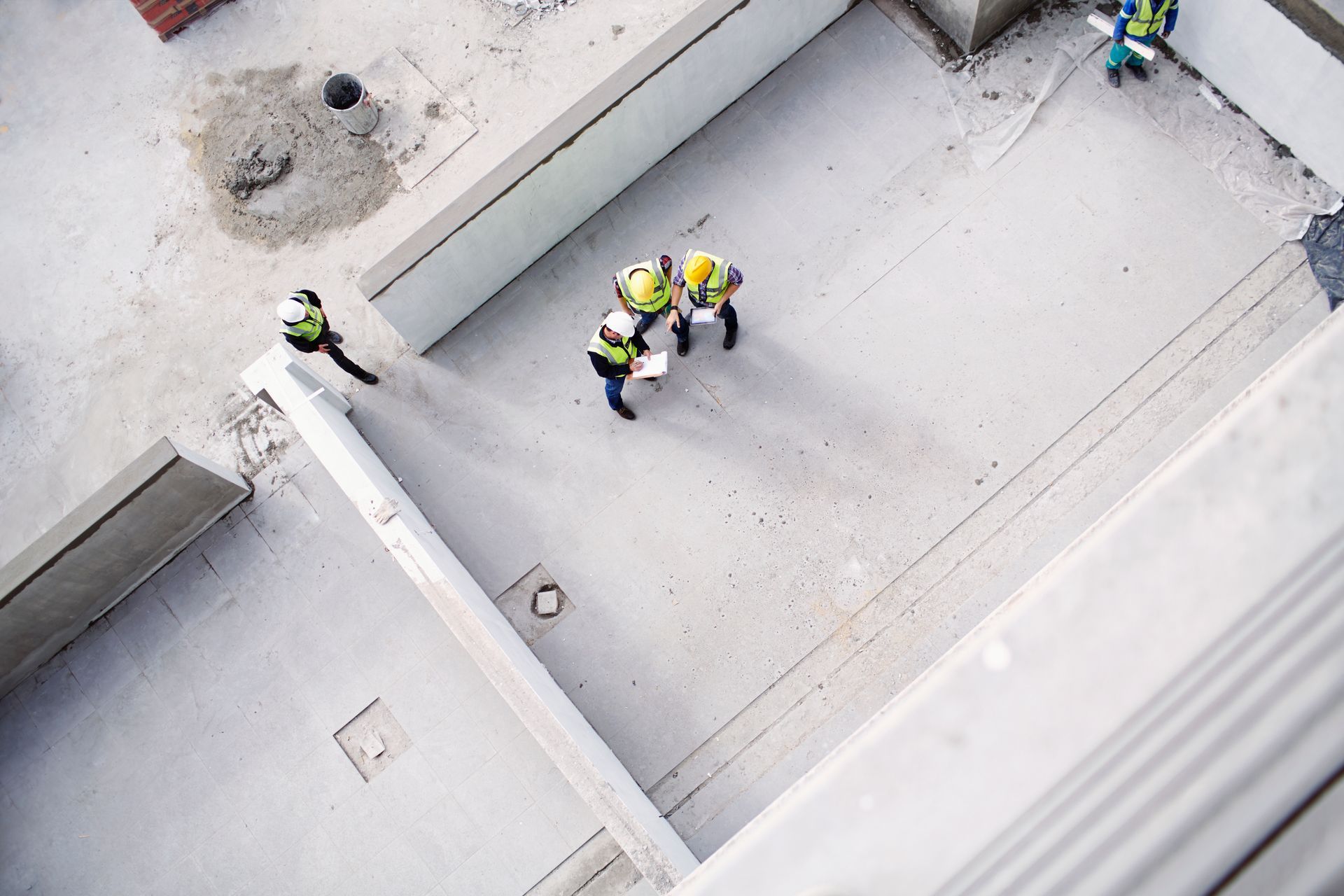 Commercial concrete contractor team reviewing blueprints on concrete rooftop. Commercial concrete contractor team reviewing blueprints on concrete rooftop.