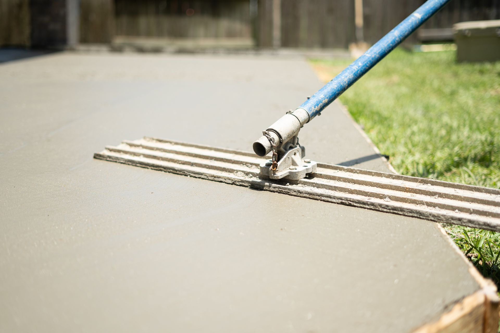 Tool smoothing freshly poured concrete on an outdoor surface. Tool smoothing freshly poured concrete on an outdoor surface.