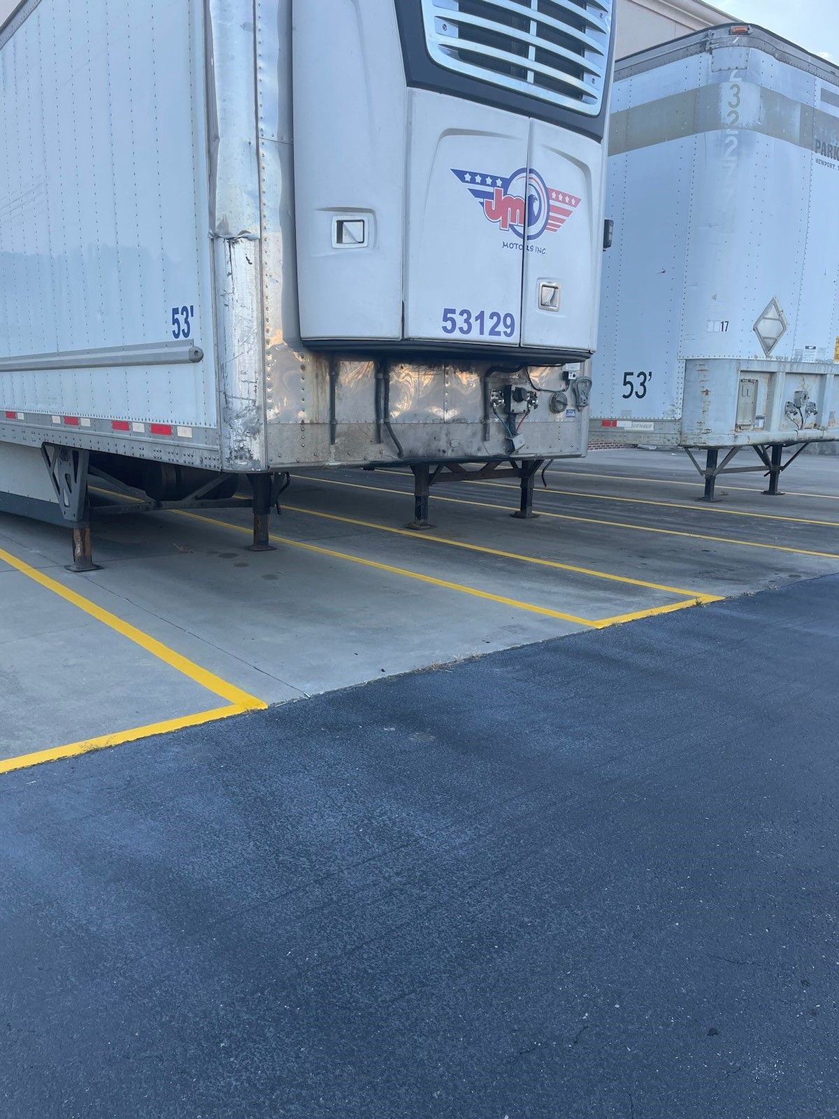 Refrigerated semi-trailer parked in a lot, number 53129 on the front.