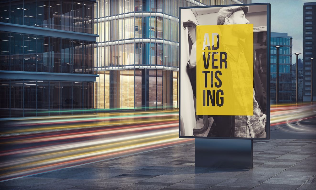 A billboard with a picture of a man on it is in front of a building.