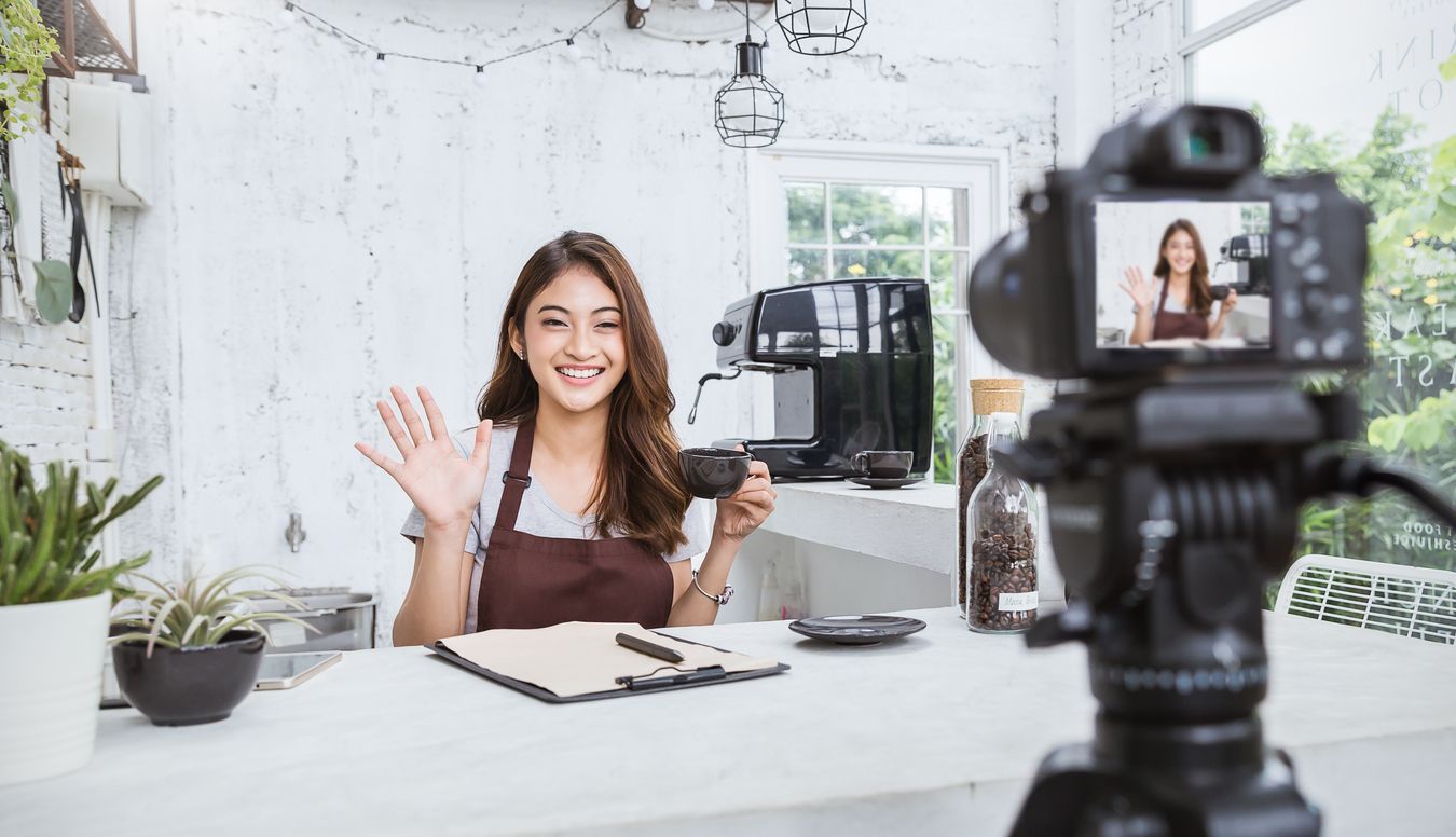 A woman is holding a cup of coffee in front of a camera.