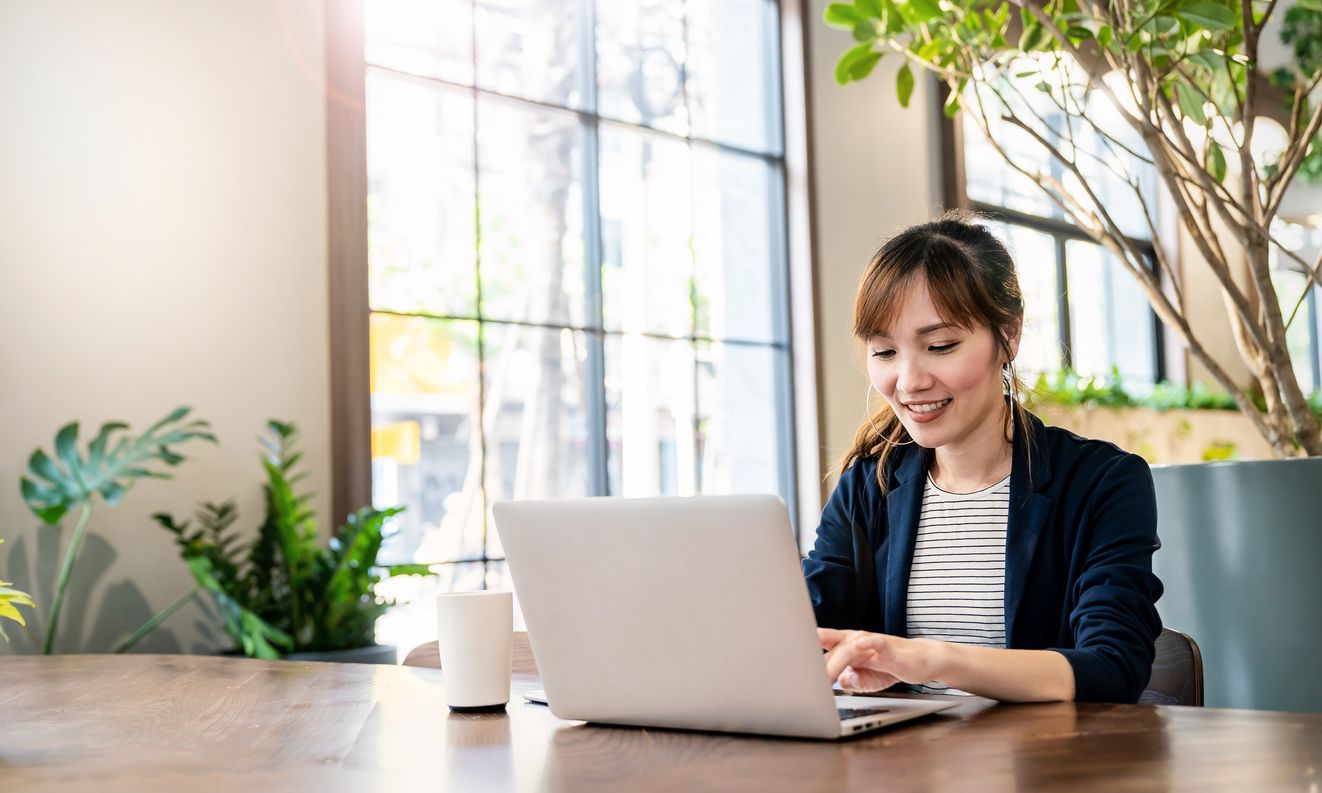 A woman is sitting at a table using a laptop computer.