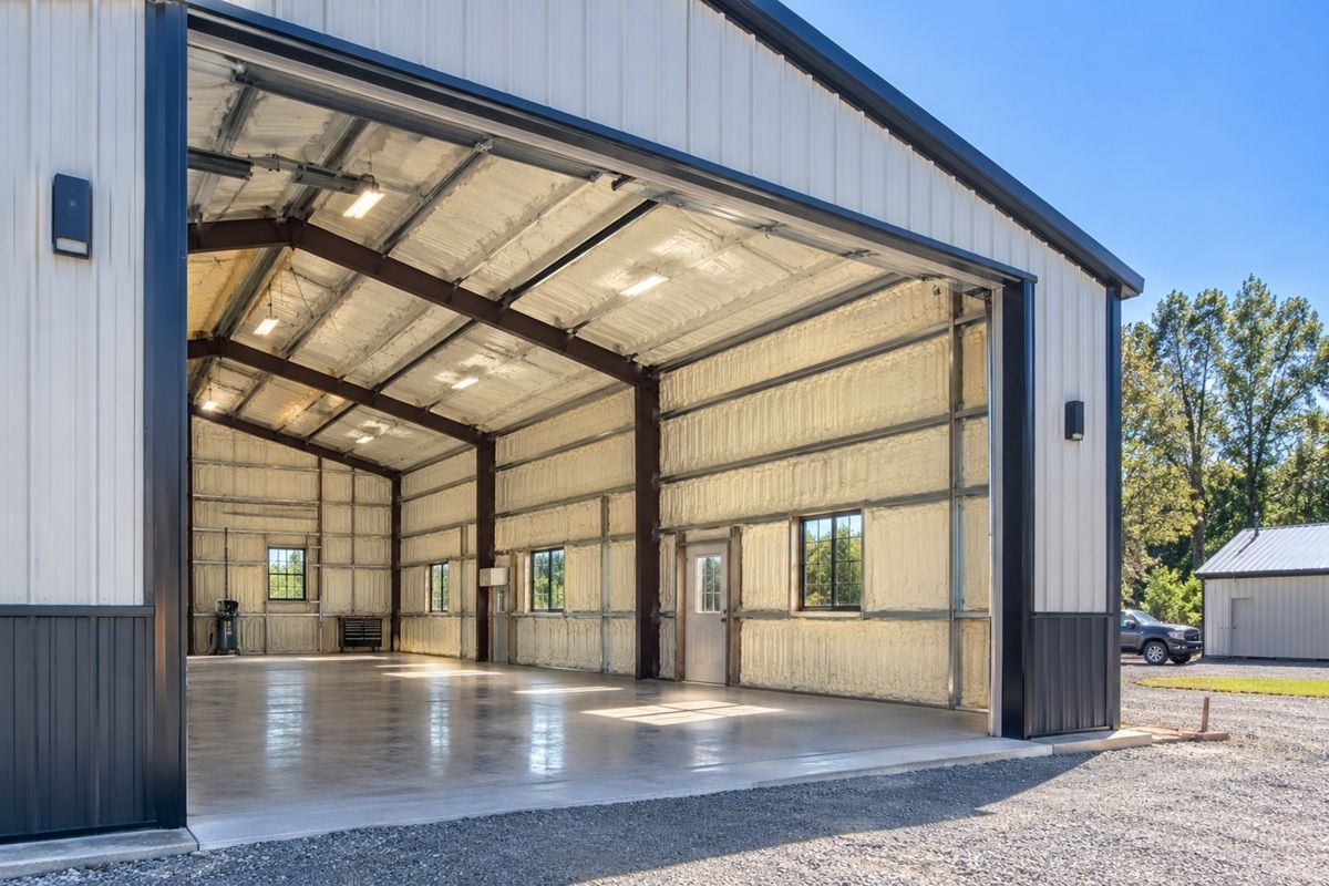 Completed metal building with spray foam insulated walls and roof, open bay door, and exterior surroundings.