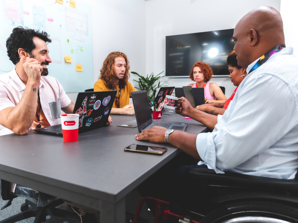 Um homem em uma cadeira de rodas está sentado à mesa com um grupo de pessoas.