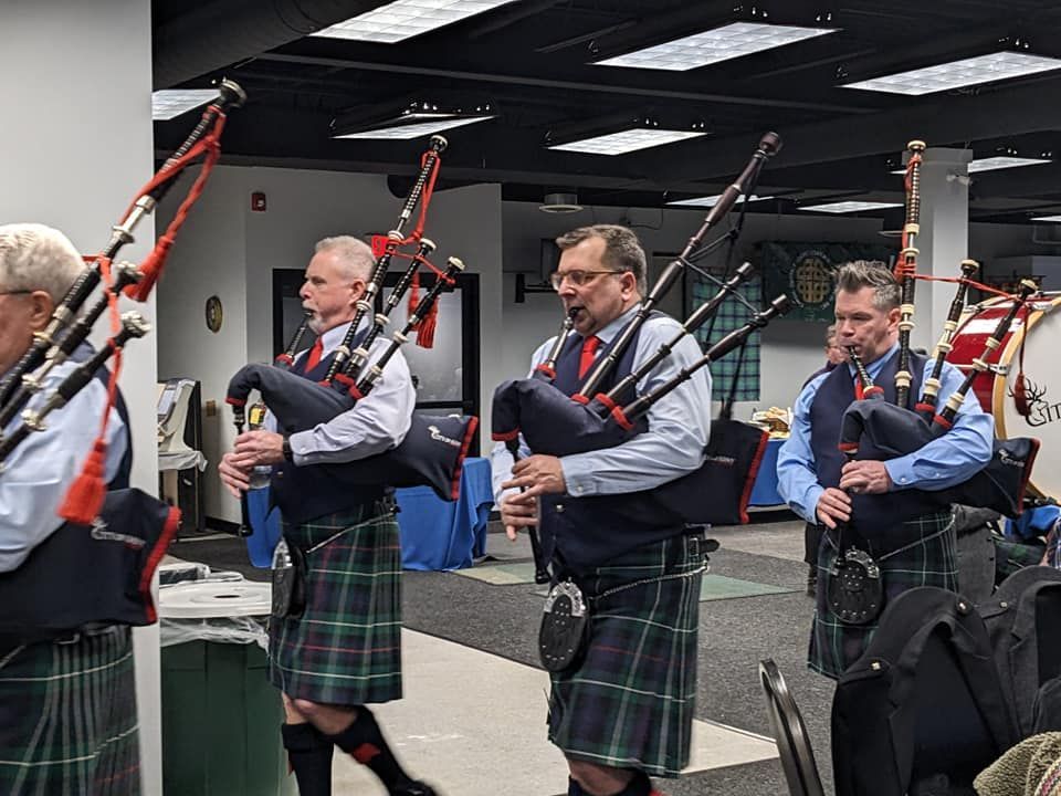 Bagpipers in kilts performing indoors at a competition or rehearsal