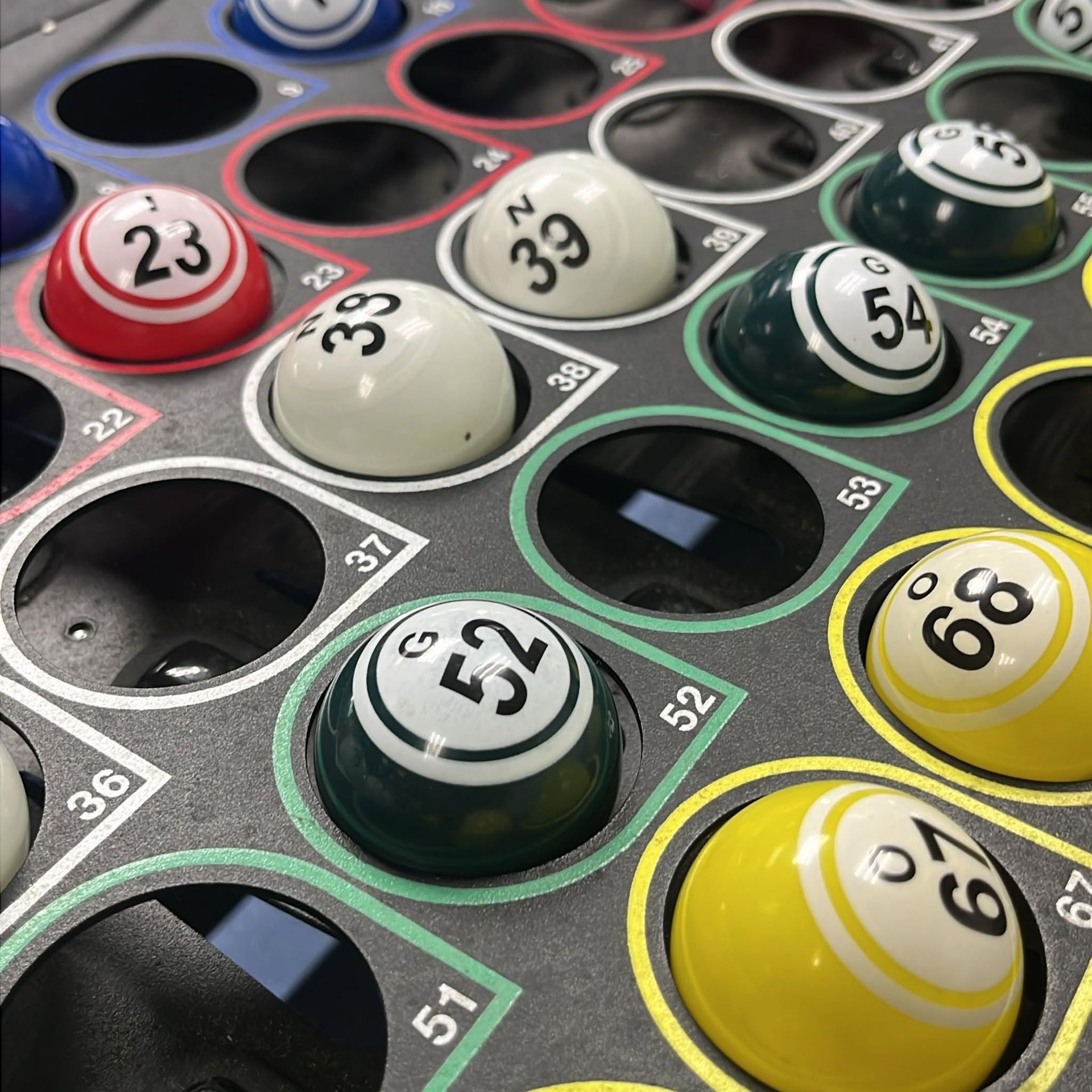 Close-up of colorful numbered bingo balls on a game board, including red 23, white 39, green 52, and yellow 68