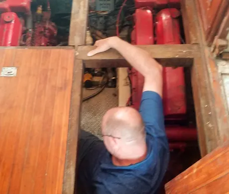 A man in a blue shirt is working on a boat engine