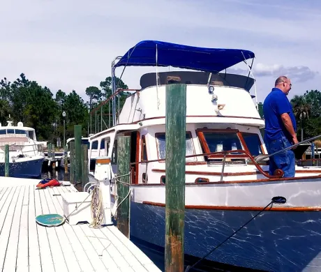 A man stands next to a boat with a blue canopy