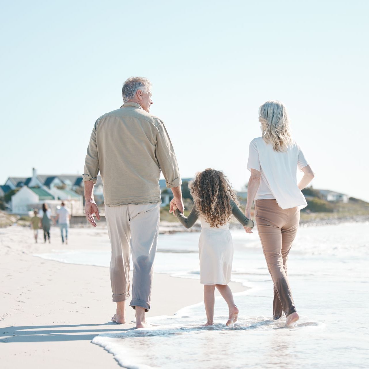 A family is walking on the beach holding hands.