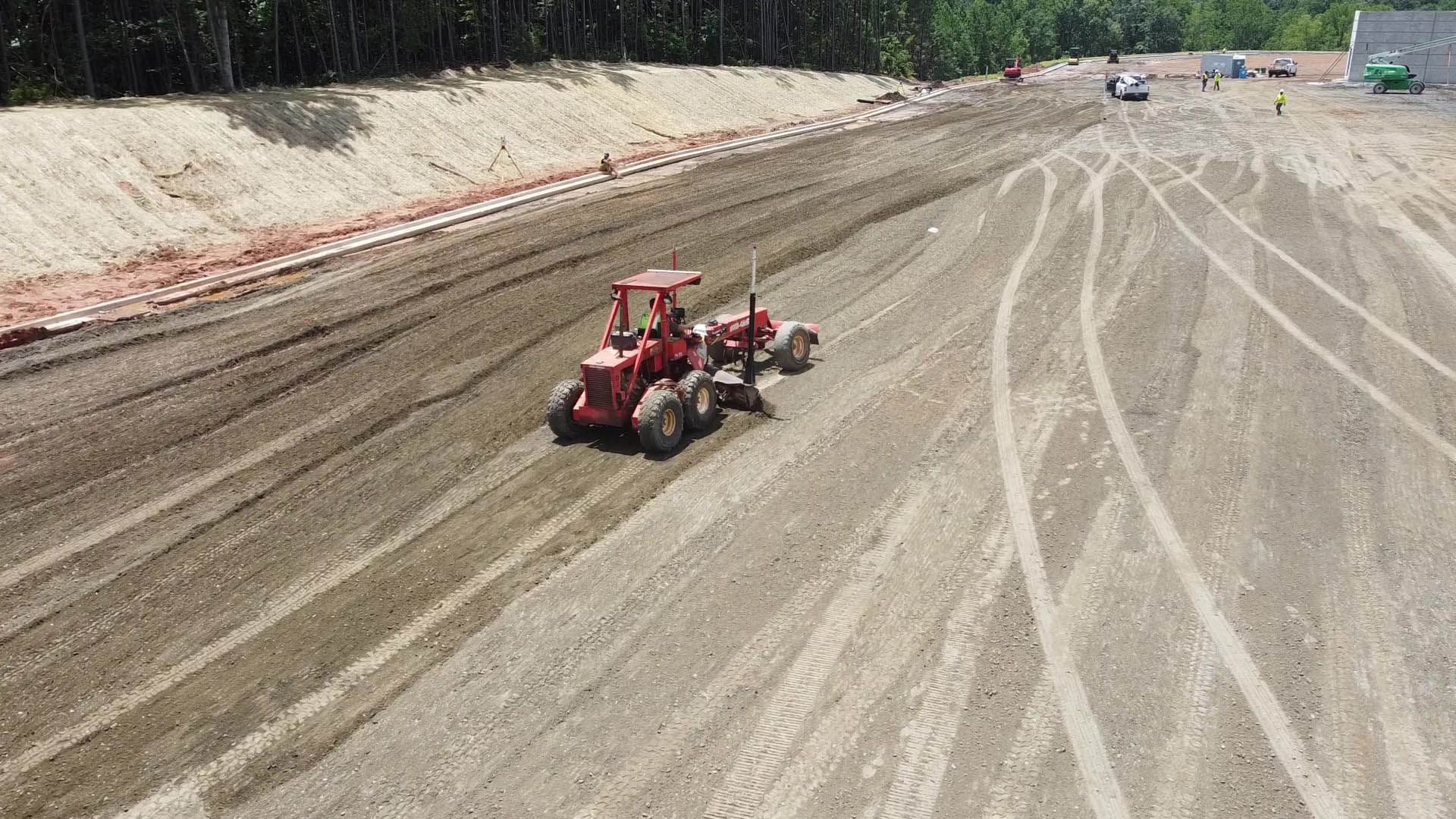 Red tractor grading dirt on a construction site.