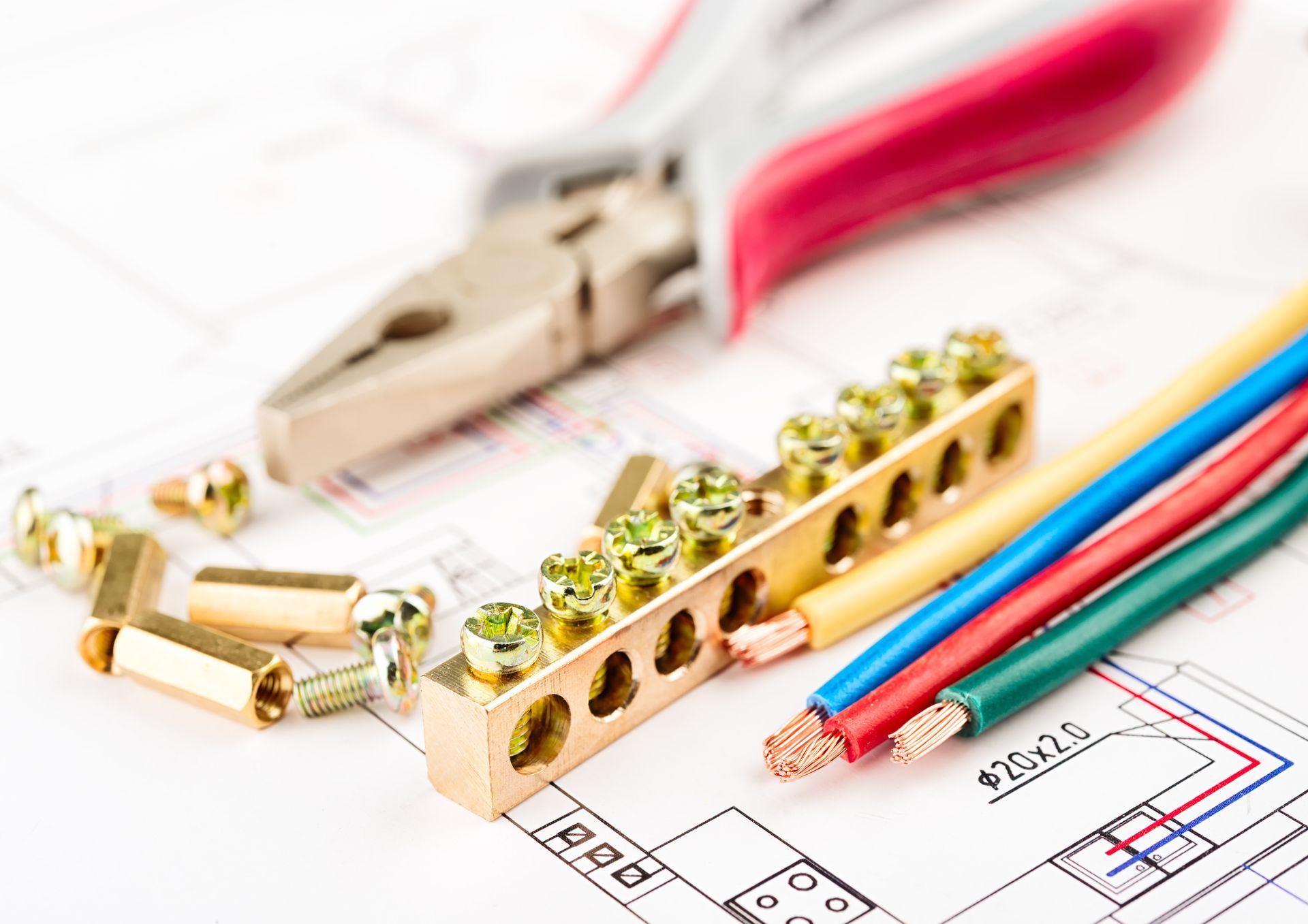 Electrical tools and wires on a blueprint; includes pliers, wire connectors, and colored wires.