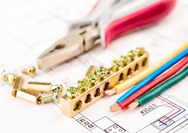 Electrical tools and wires on a blueprint; includes pliers, wire connectors, and colored wires.
