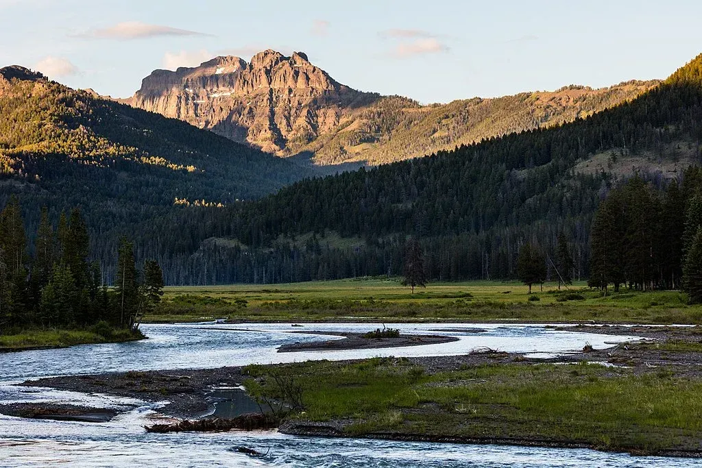 Mountain lake and forest at sunset with rocky peaks in the background