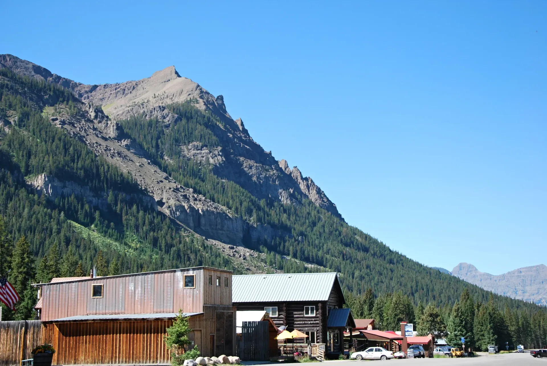 Mountain town beneath a rocky, forested peak under a clear blue sky