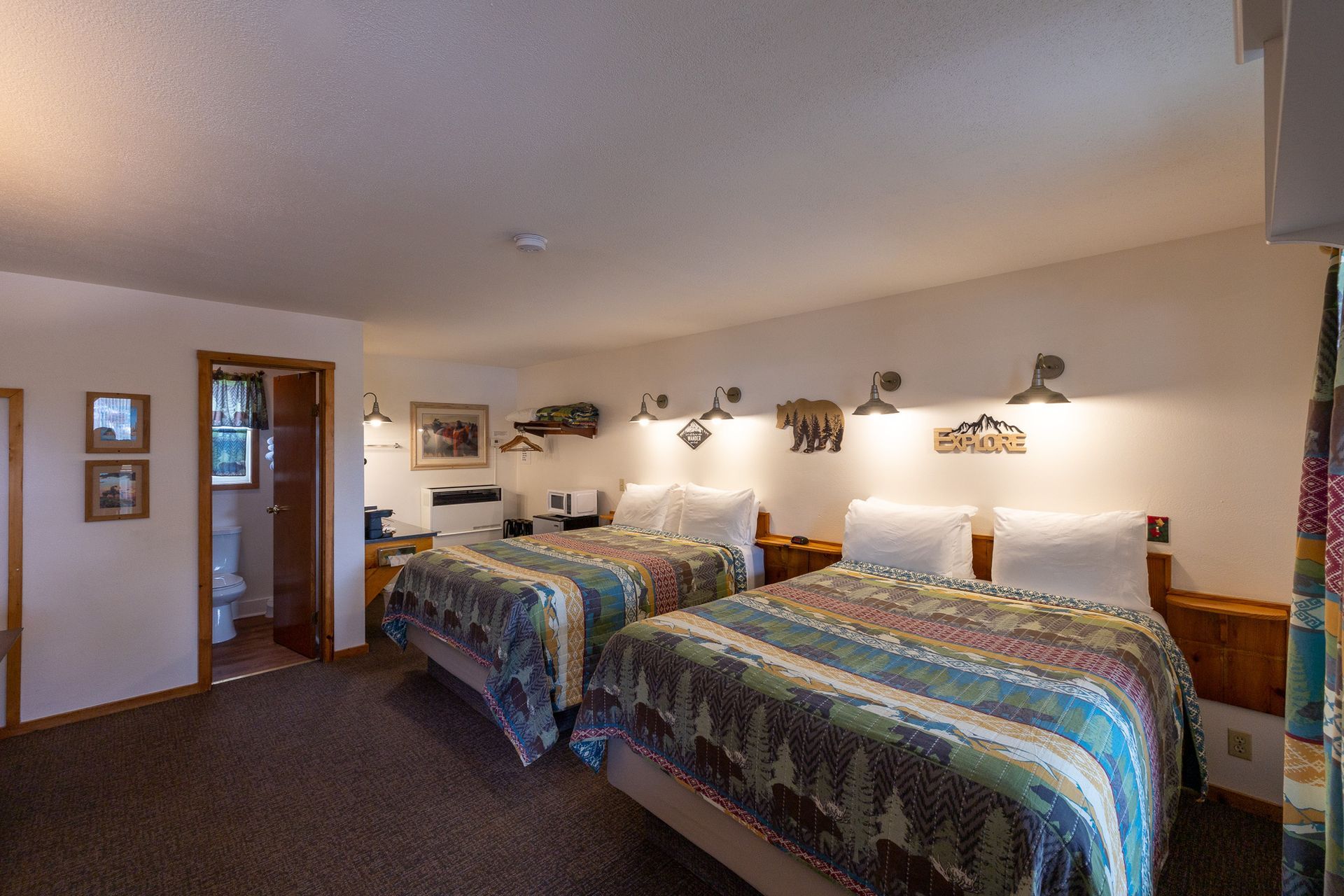 Hotel room with two double beds, wall art, and lamps in a carpeted interior