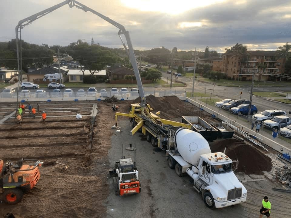 A Concrete Mixer Truck is Driving Down a Construction Site — Mackie's Concrete Pumping In Bulahdelah, NSW