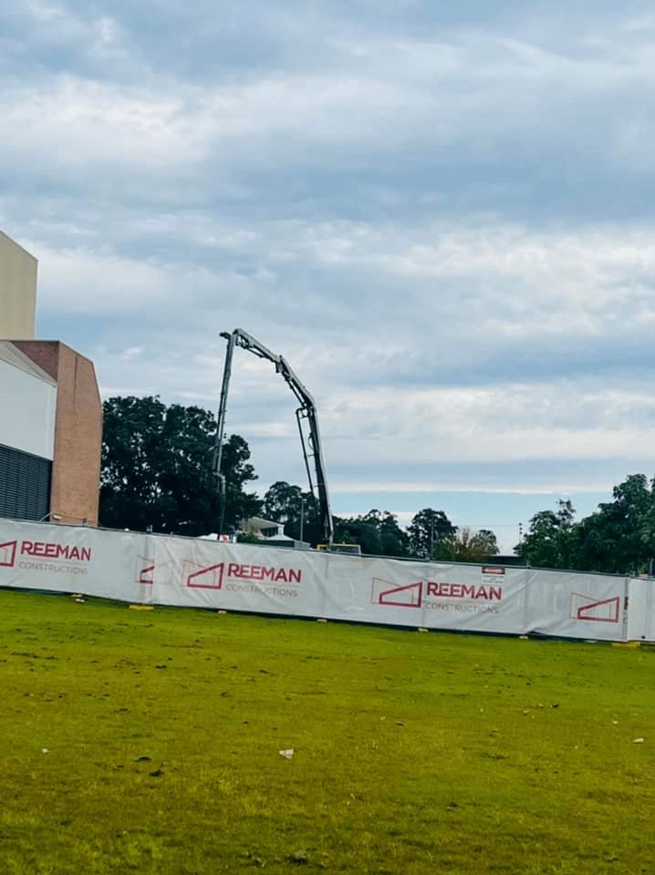 A Construction Site With a Fence and a Crane in the Background — Mackie's Concrete Pumping In Bulahdelah, NSW