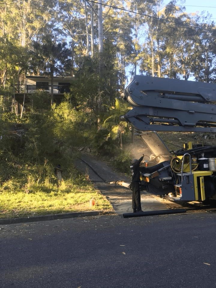 A Concrete Pump is Sitting on the Side of the Road Next to a House — Mackie's Concrete Pumping In Harrington, NSW