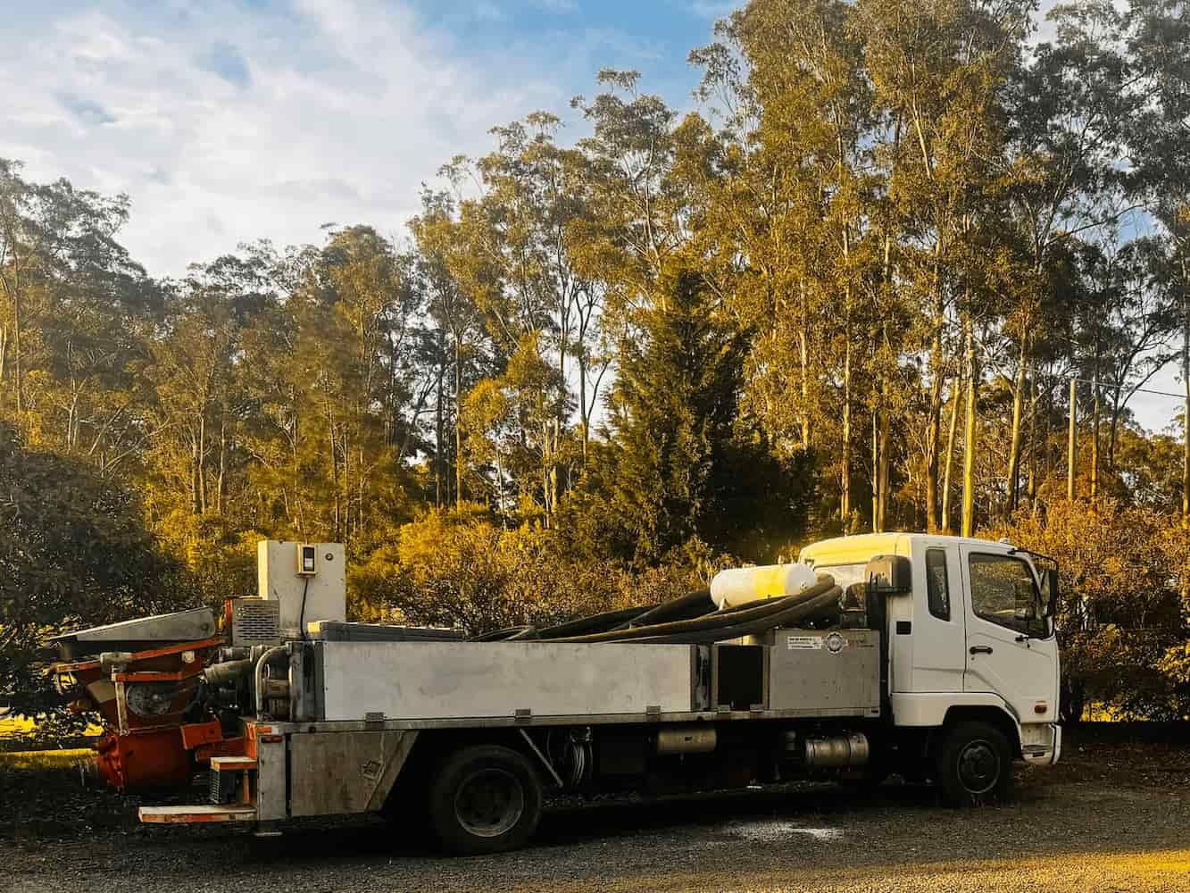 A White Truck is Parked in a Parking Lot With Trees in the Background — Mackie's Concrete Pumping In Taree, NSW
