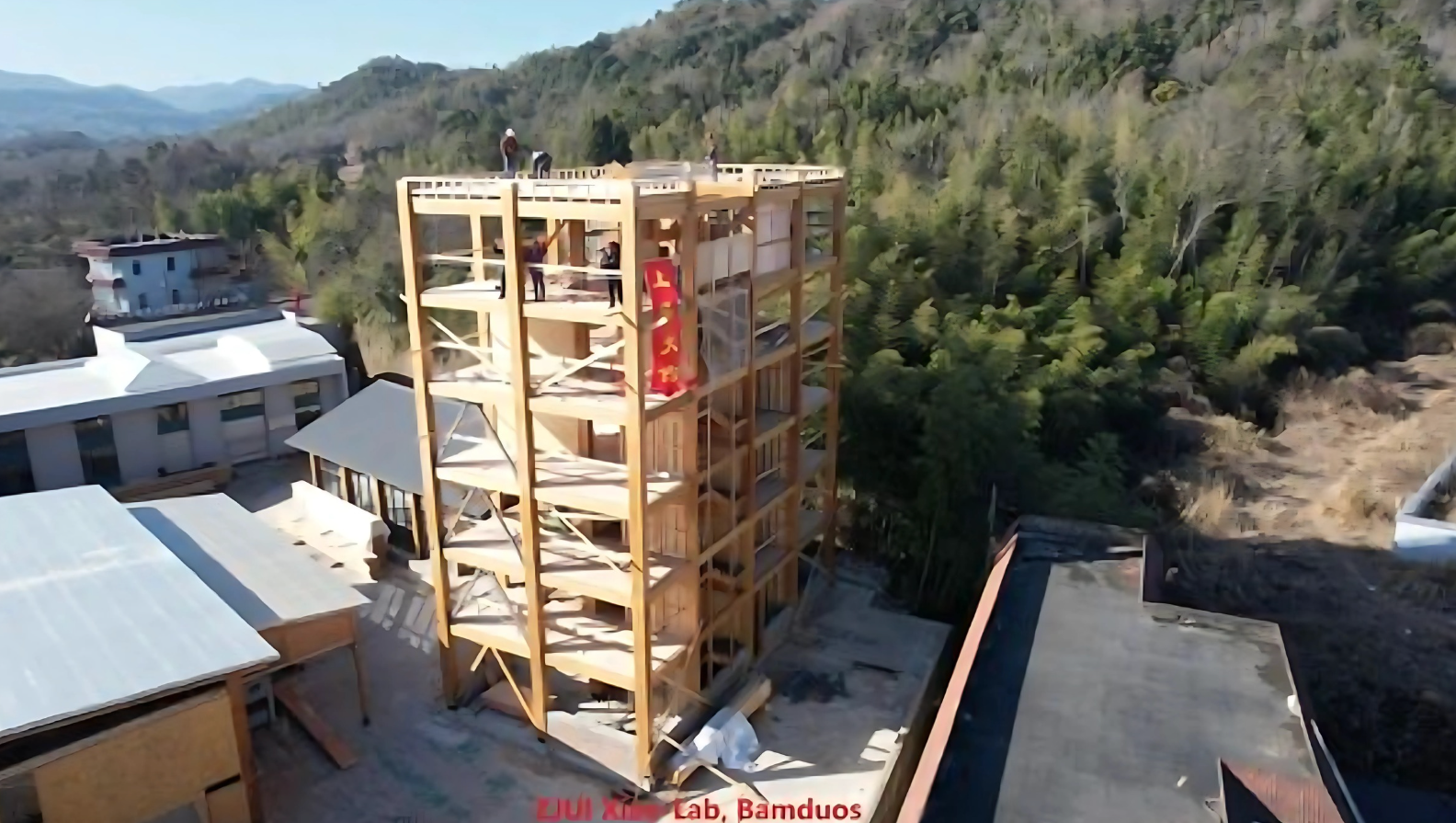 An aerial view of a building under construction in the middle of a forest