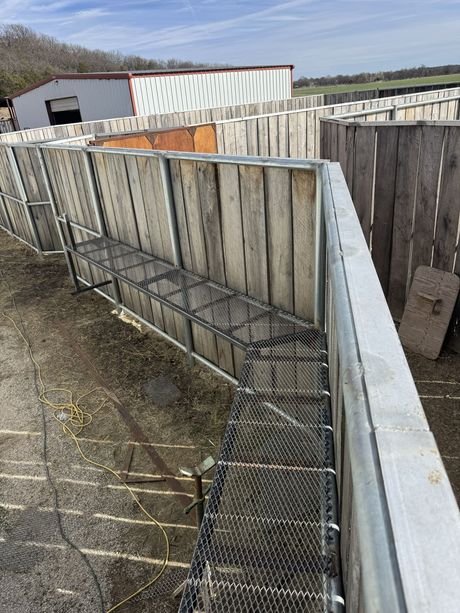 Tarp-covered backyard corner with leaning wooden fence and wire mesh along a gravel path
