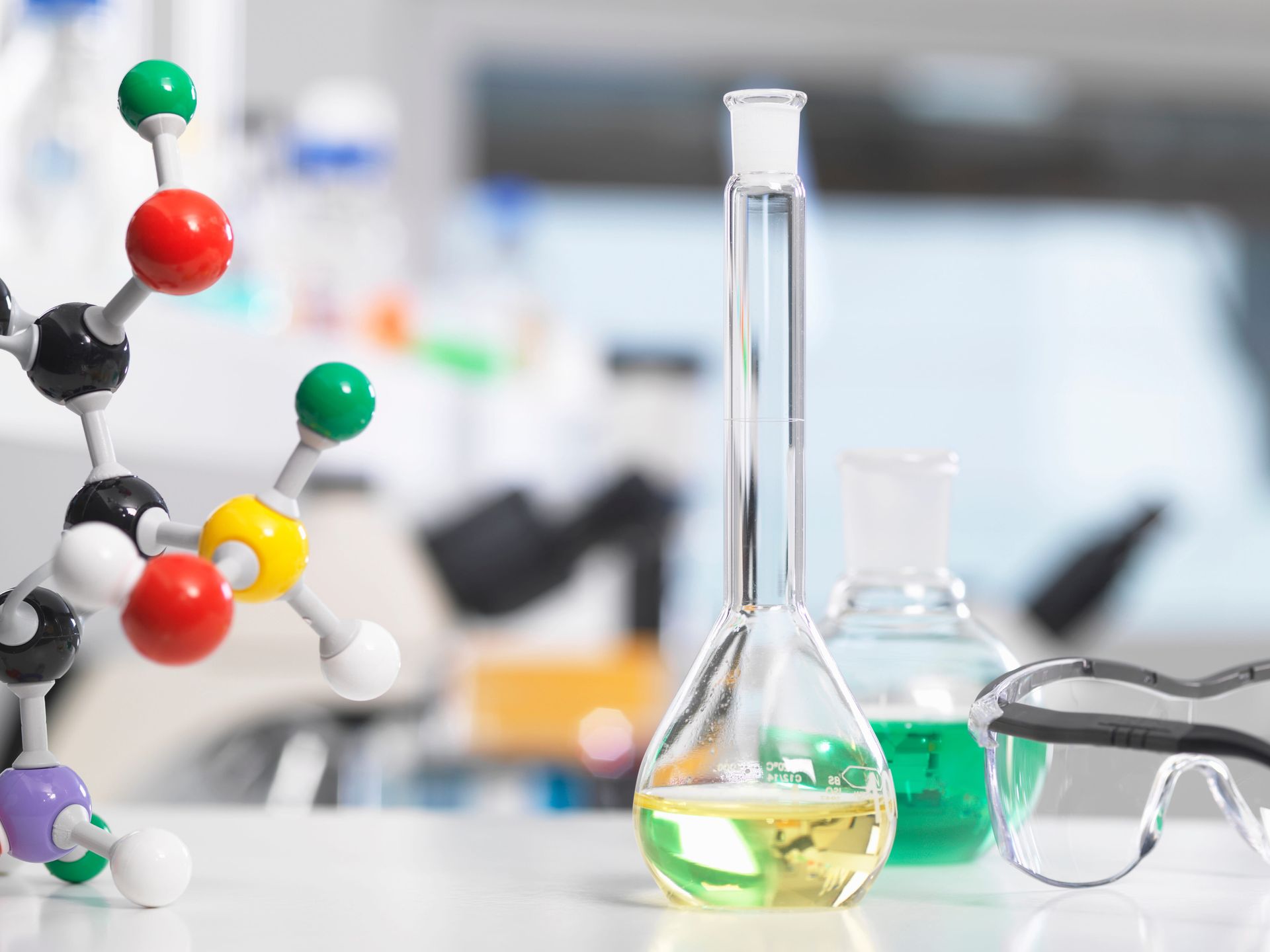 Laboratory glassware with colorful chemical models and safety goggles on a lab bench