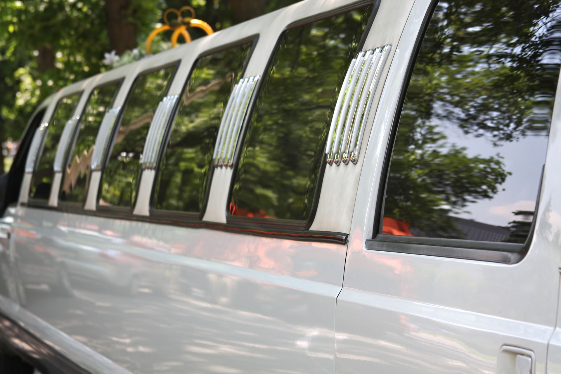 White limousine with tinted windows parked outdoors under trees White limousine with tinted windows parked outdoors under trees