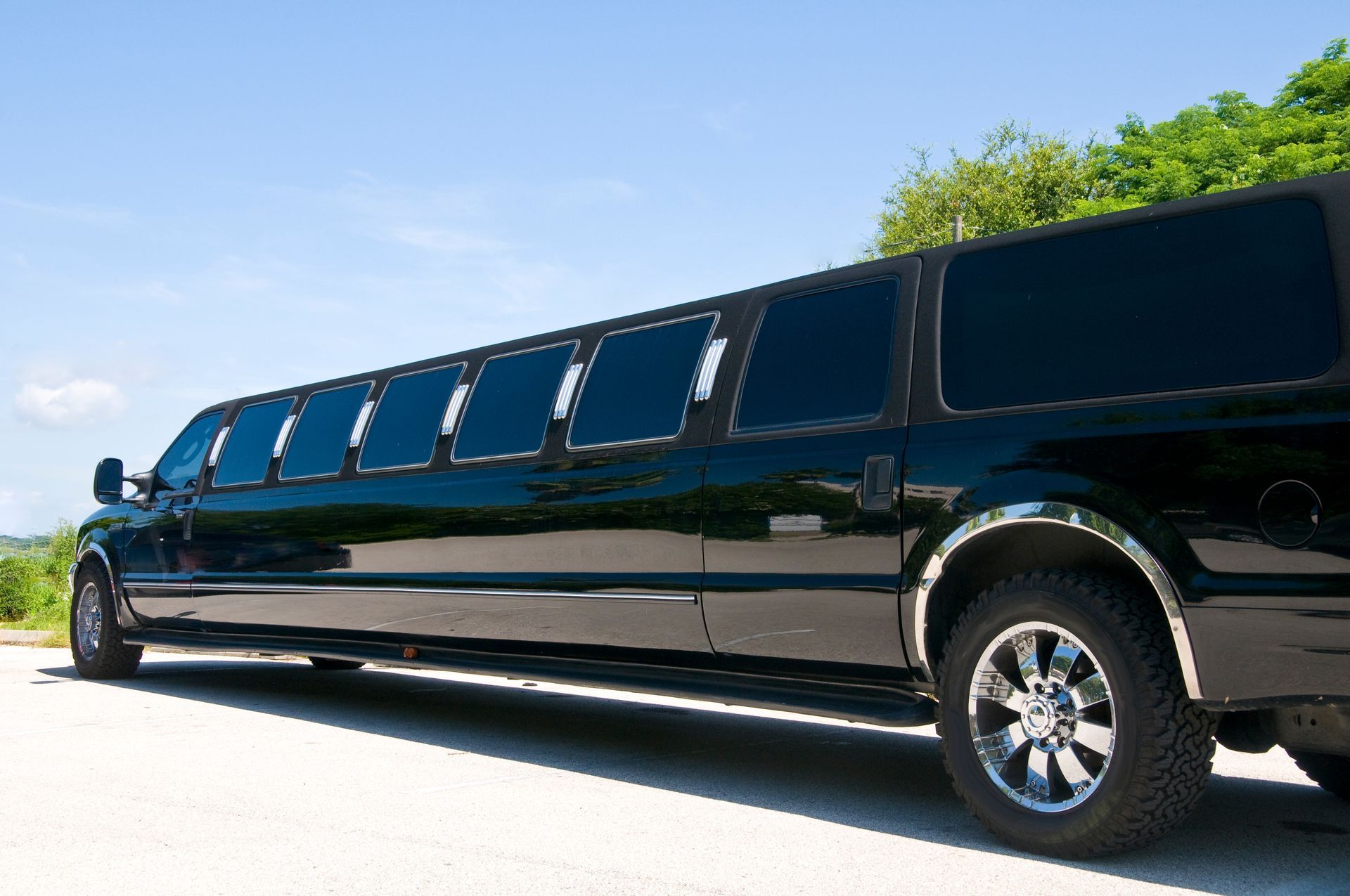Black stretch limousine parked on a sunny road under a blue sky Black stretch limousine parked on a sunny road under a blue sky