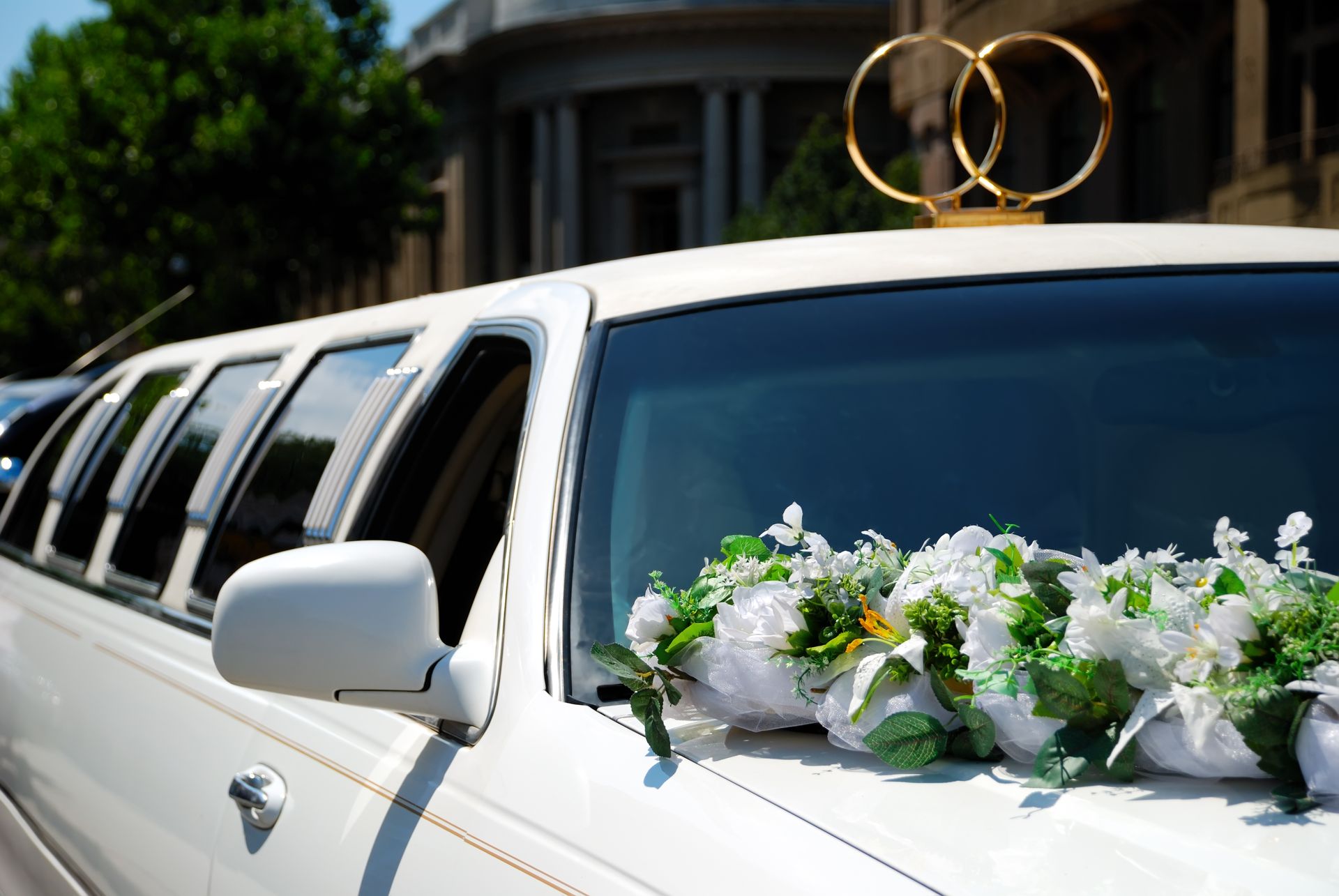 White limousine decorated with white flowers and gold wedding rings on top White limousine decorated with white flowers and gold wedding rings on top