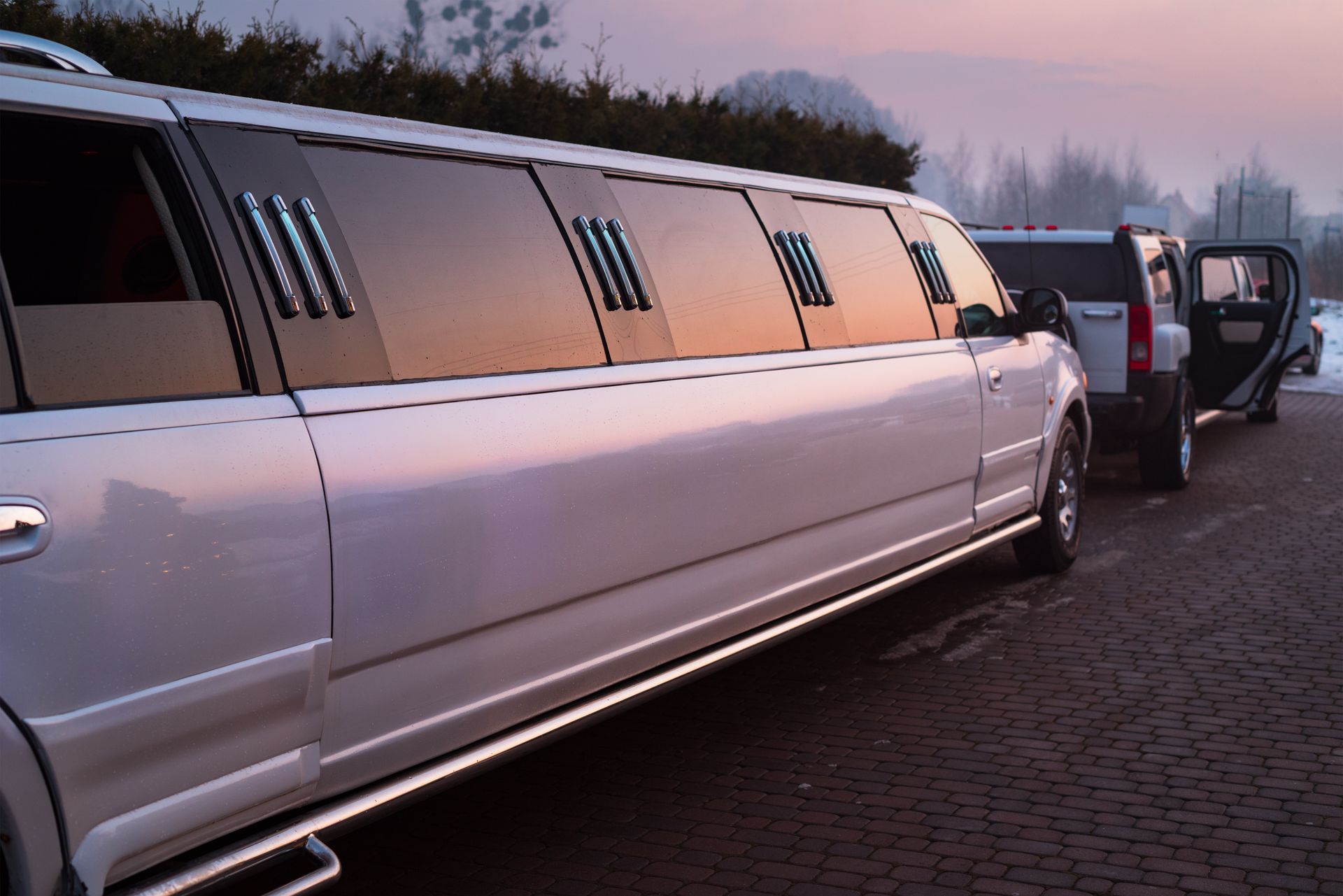 White stretch limousine parked on a road, with its rear door open. White stretch limousine parked on a road, with its rear door open.