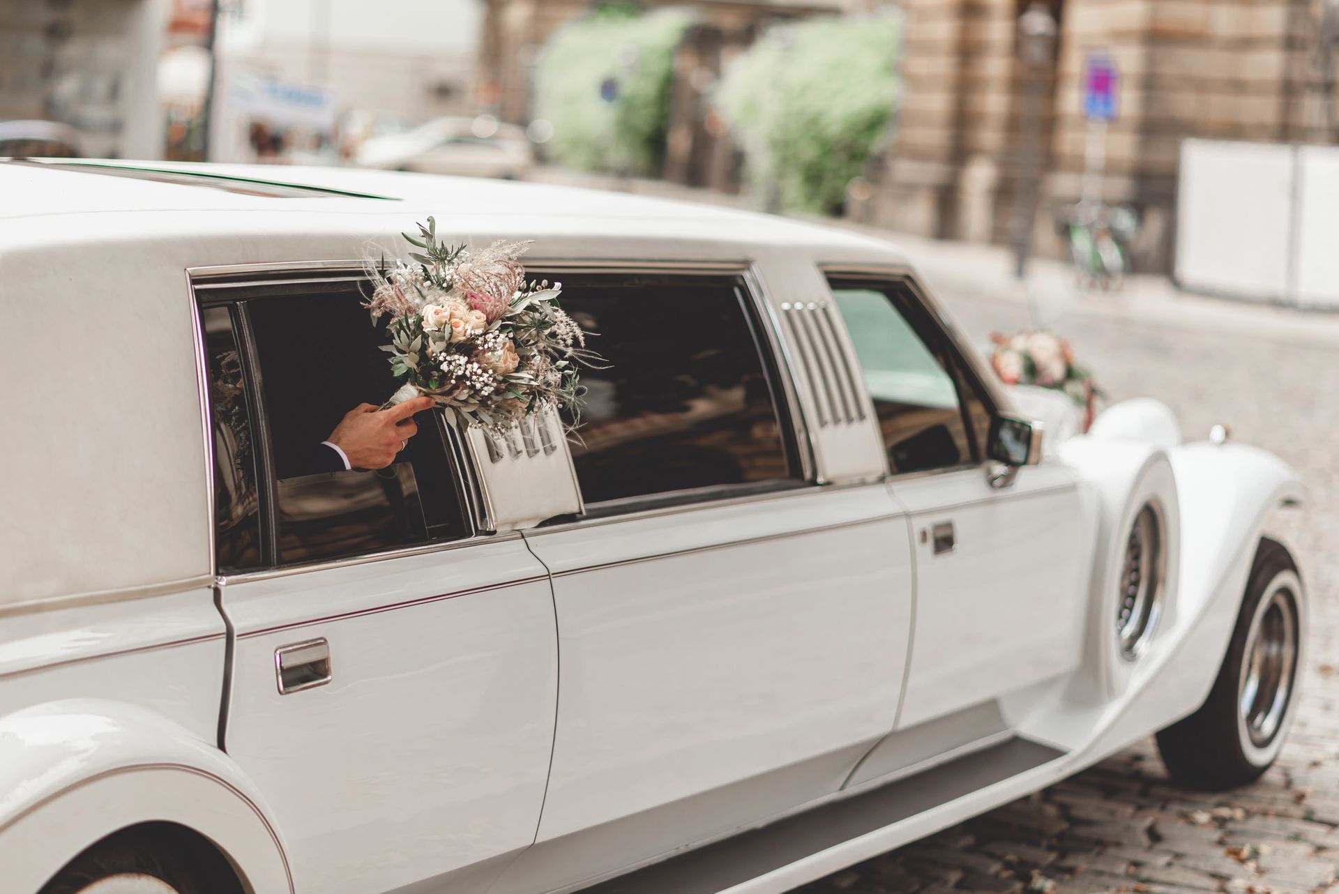 White limousine with a bouquet in the window, parked on a cobblestone street. White limousine with a bouquet in the window, parked on a cobblestone street.