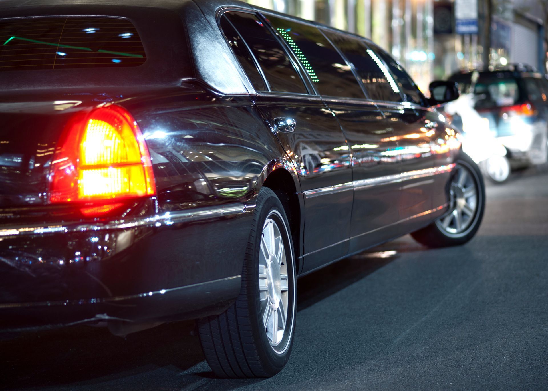 Dark sedan driving at night on a city street, with red taillights glowing. Dark sedan driving at night on a city street, with red taillights glowing.