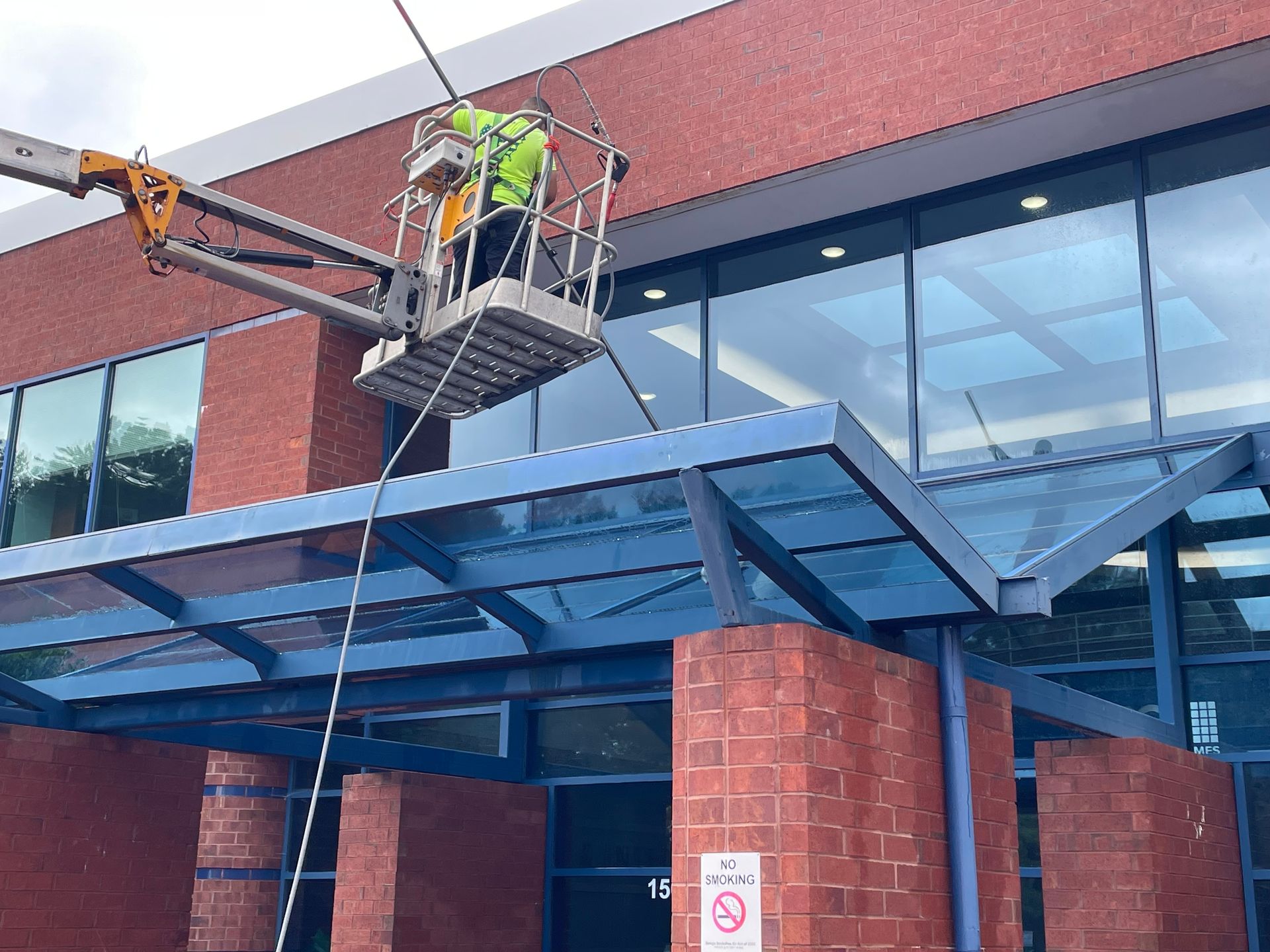 Worker in a boom lift beside a brick commercial building