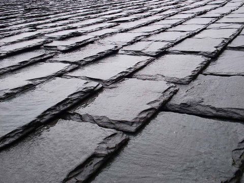 Close-up of dark slate roof tiles with textured edges