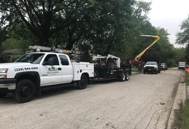 Work truck and trailer with tree trimming equipment on a residential street in Bristol, WI