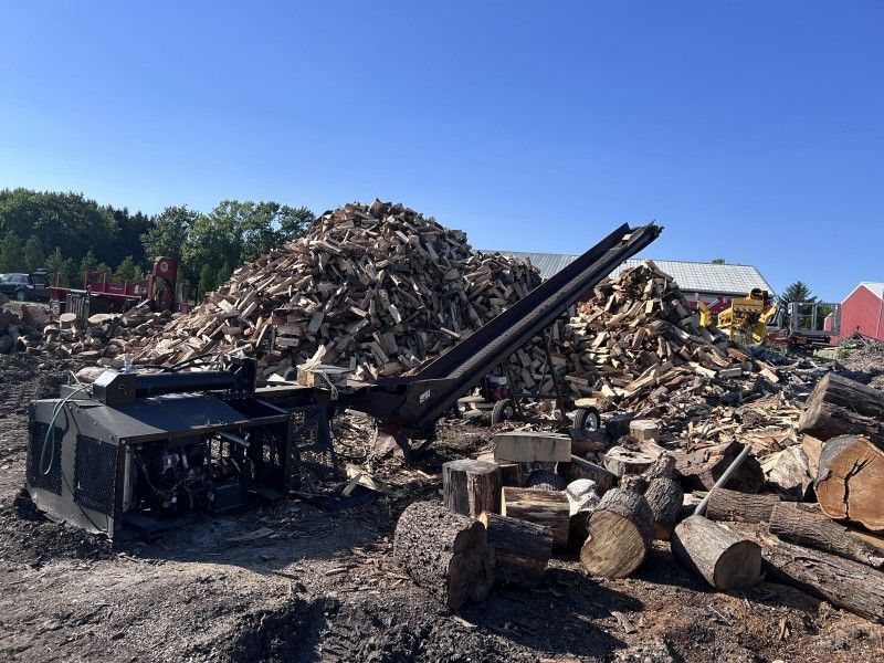 Firewood processing yard with conveyor and rock/debris pile near Kenosha, WI