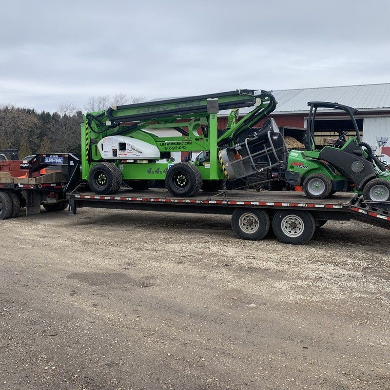 Green articulating boom lift loaded on trailer for precision tree pruning in Kenosha, WI