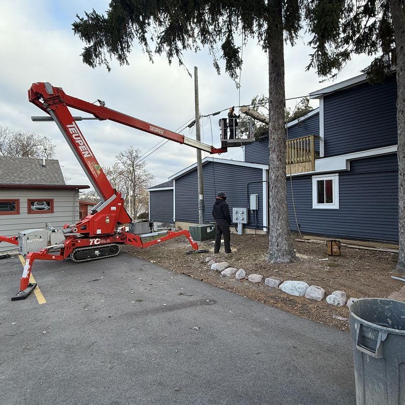 Bucket lift raised beside a home during tree trimming service