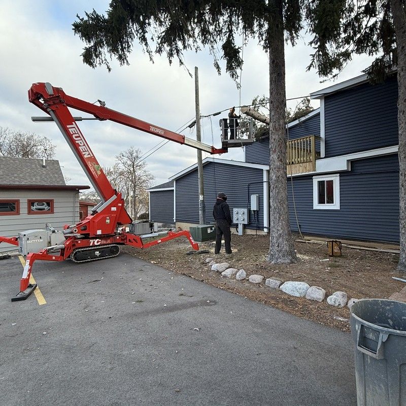 Bucket lift trimming a tree beside a home in Bristol, WI