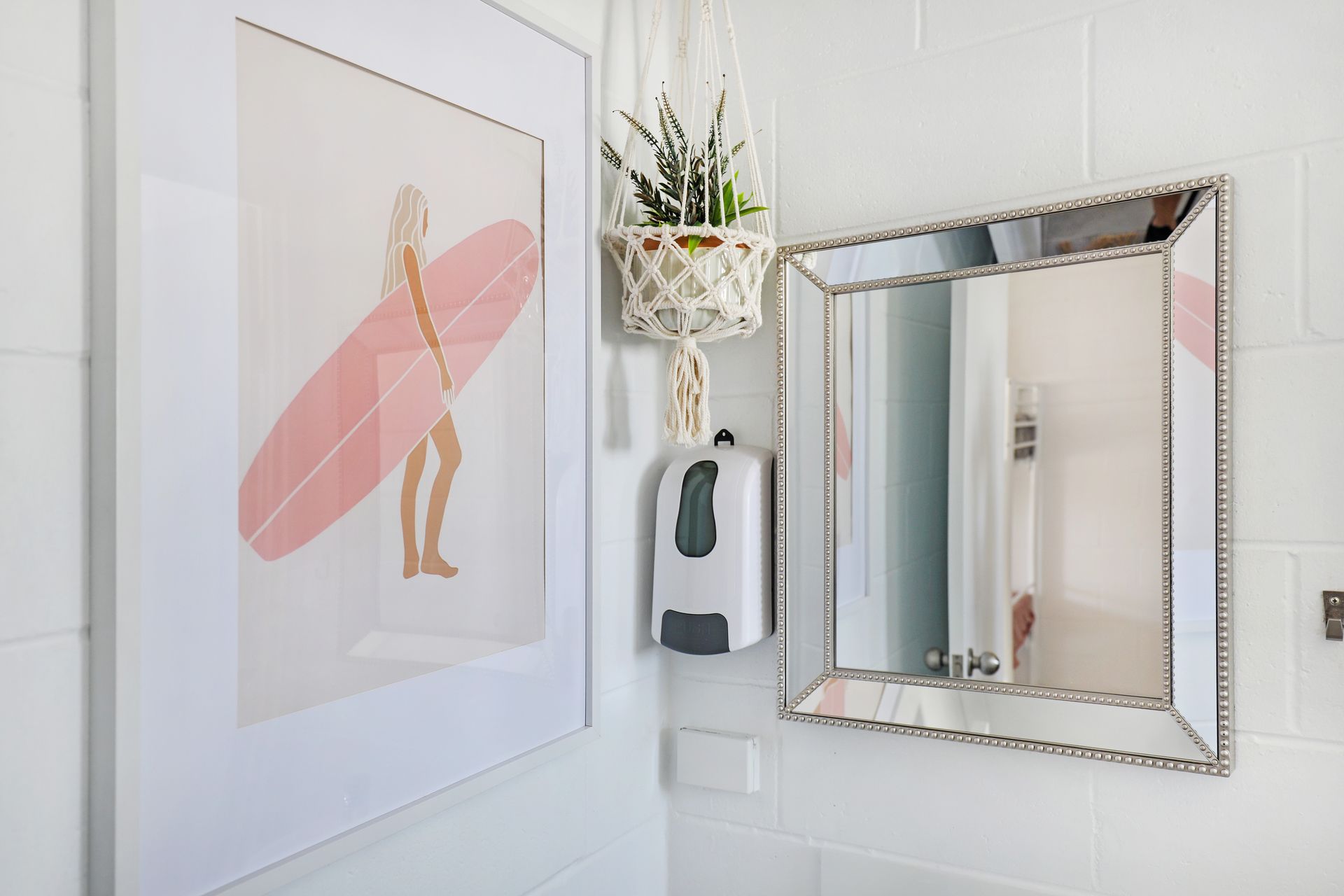 A bathroom with a picture of a woman holding a surfboard and a mirror.
