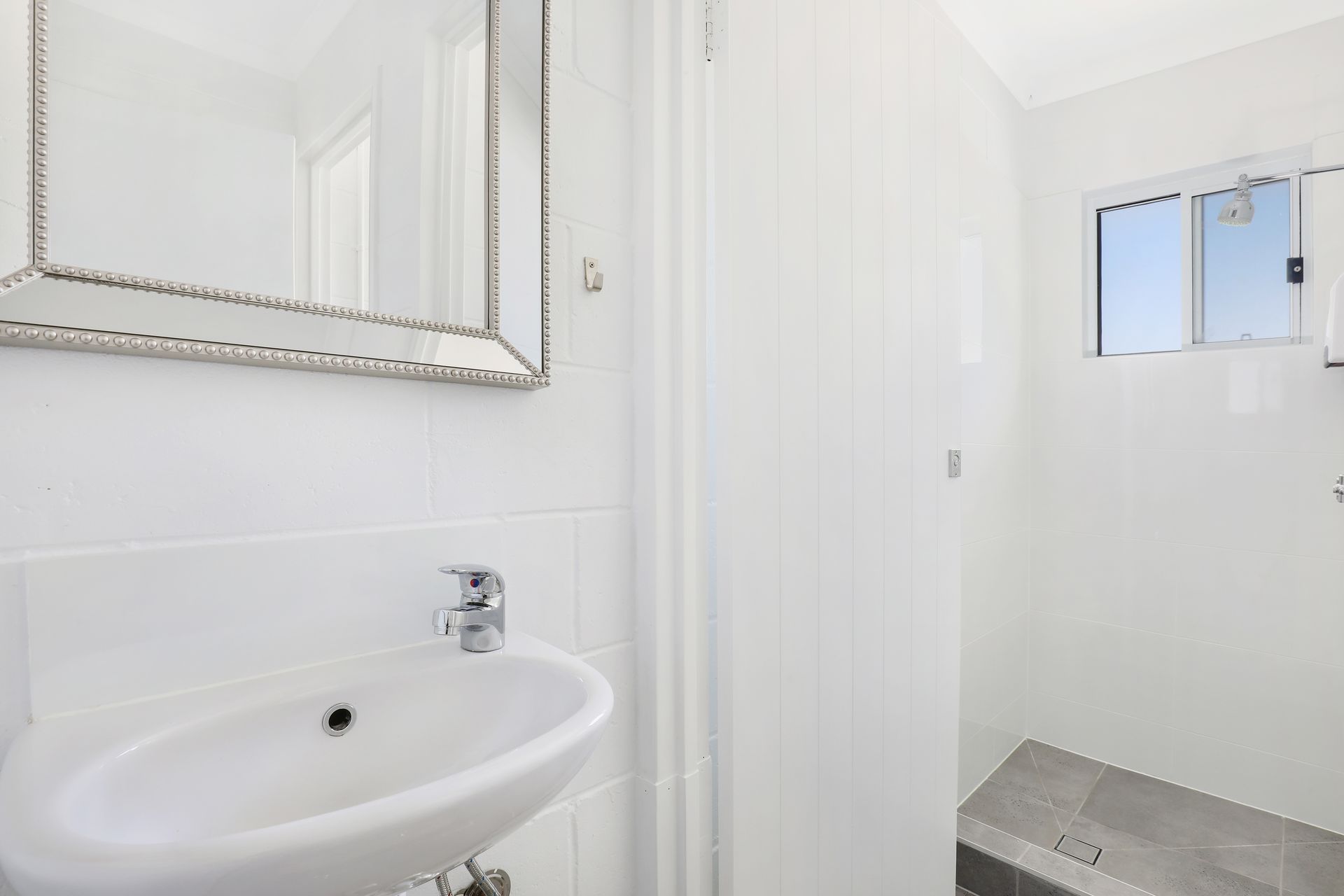 A bathroom with a sink , mirror and shower.