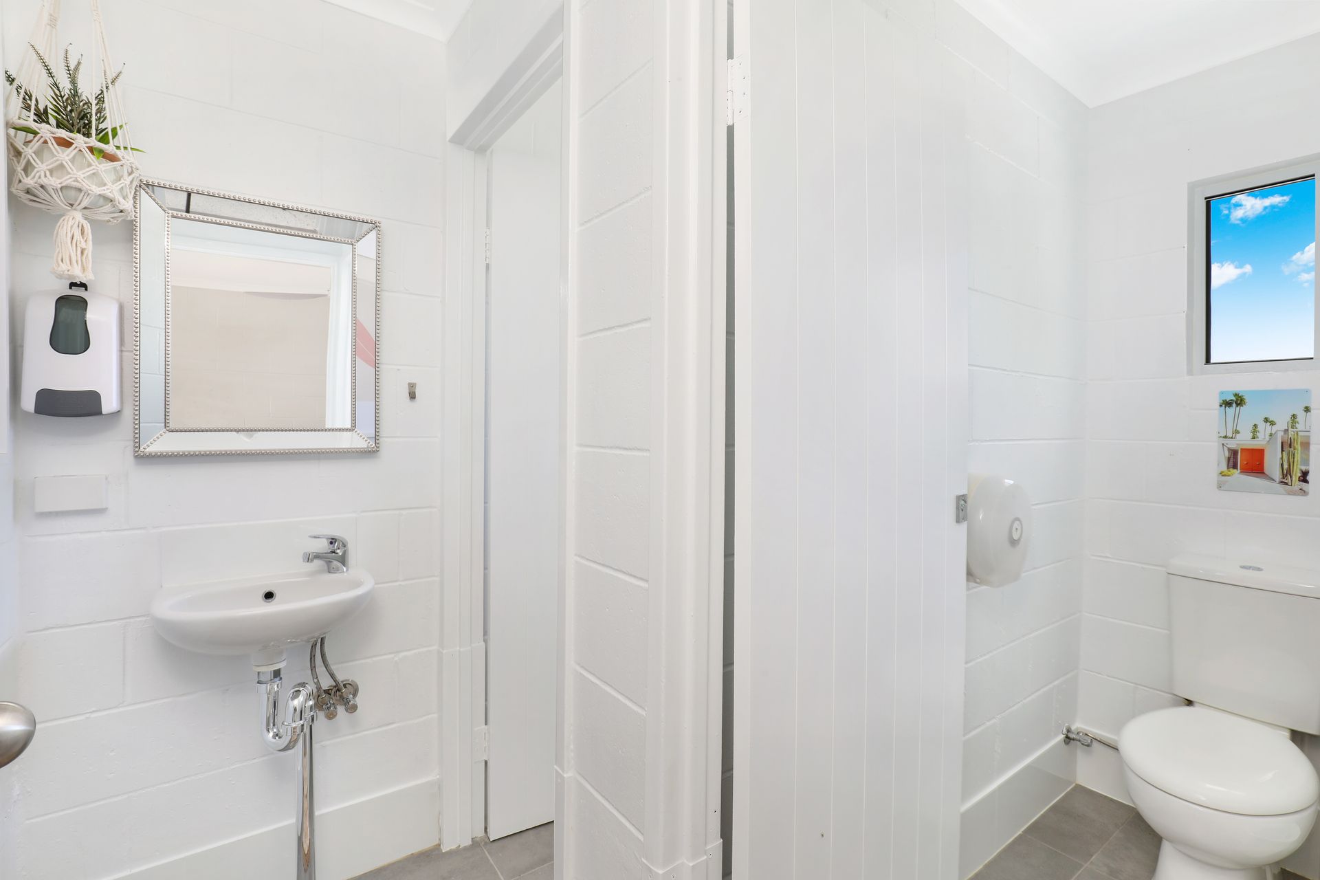 A bathroom with a sink , toilet , mirror and window.