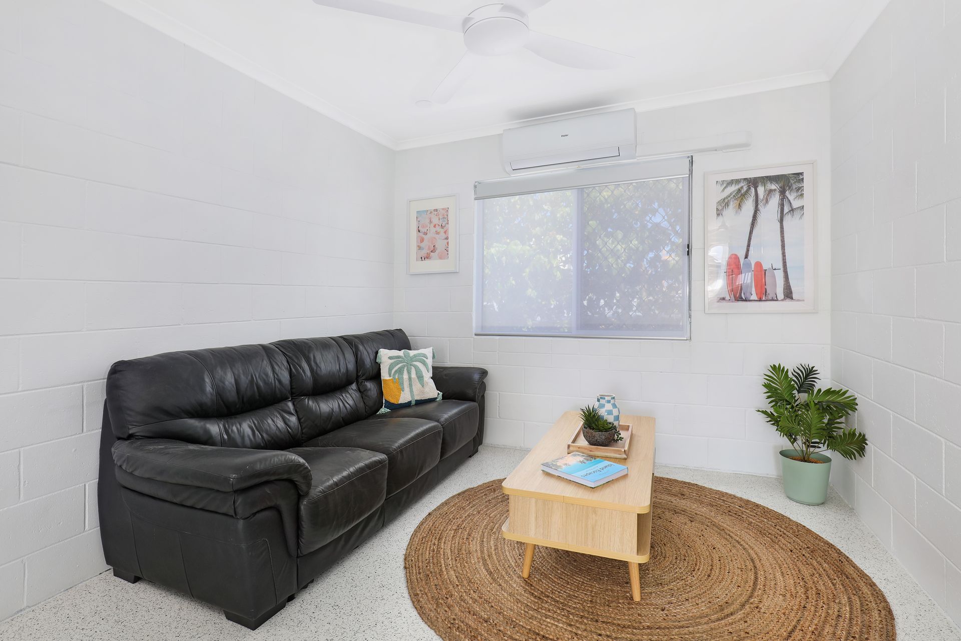 A living room with a black couch , coffee table , and rug.